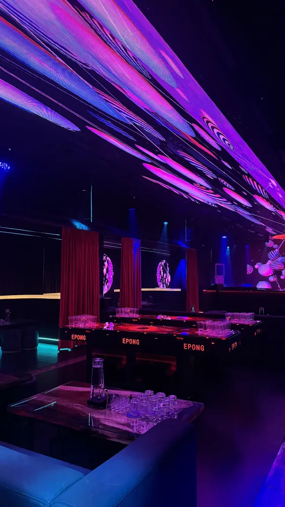 Booth tables and glassware beneath purple ceiling panels at Babylon Club, Bukit Jalil